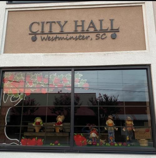Window display at City Hall in Westminster, SC, featuring scarecrows and apple decorations.