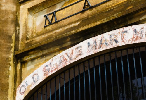 Close-up of the weathered sign reading "Old Slave Mart" on a historic building entrance.