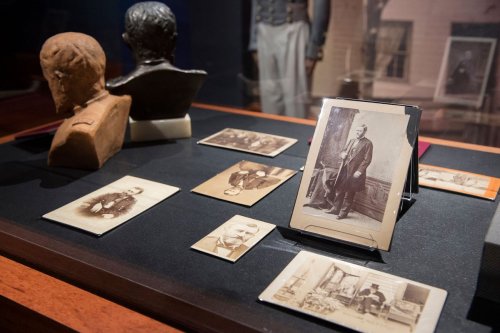 A display case featuring vintage photographs and busts, showcasing historical figures and artifacts.