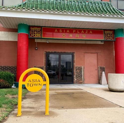 Entrance to Asia Plaza featuring a red and green awning, decorative columns, and a yellow sign reading "Asia Town."