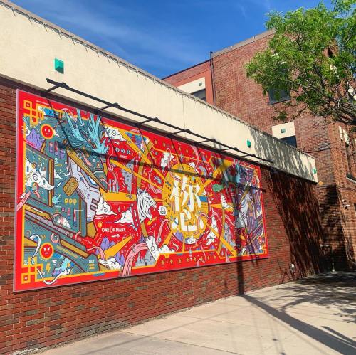 Colorful mural featuring vibrant designs and characters on a brick wall, set against a clear blue sky.