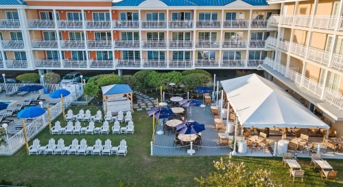 Aerial view of a hotel courtyard with lounge chairs, umbrellas, and a tented dining area.