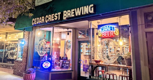 Exterior of Cedar Crest Brewing with neon signs, showcasing a welcoming atmosphere and outdoor seating.