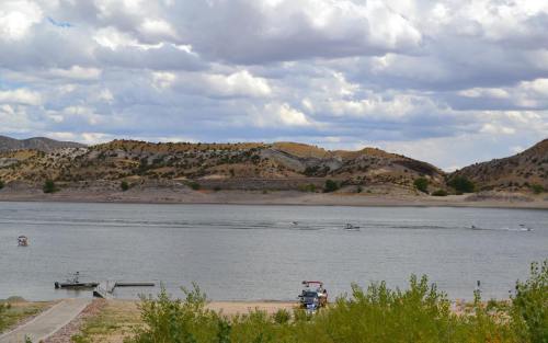 A serene lake surrounded by hills, with boats on the water and a cloudy sky above.