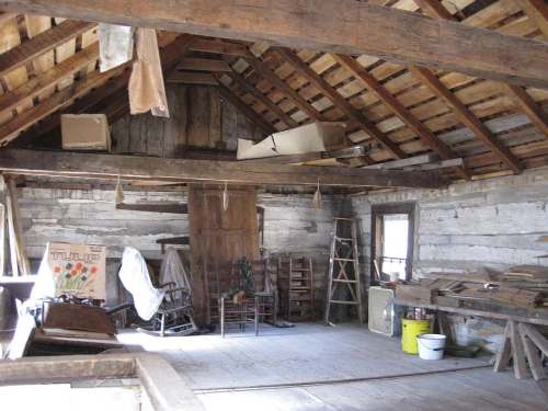 Interior of a rustic attic with wooden beams, old furniture, and scattered boxes, creating a vintage atmosphere.