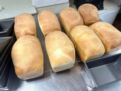 Freshly baked loaves of bread cooling on a wire rack in a kitchen setting.