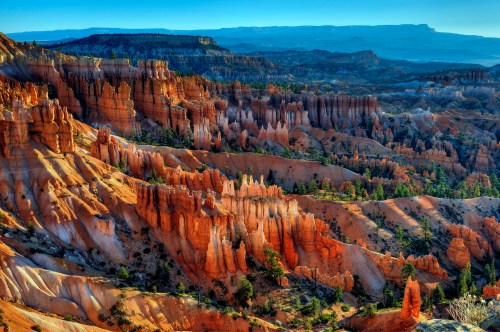 Vibrant orange and red rock formations in a canyon landscape under a clear blue sky, showcasing natural beauty.