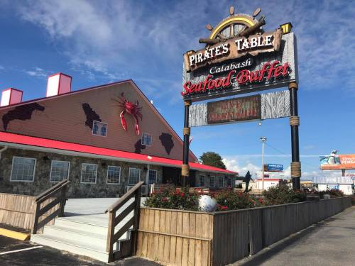 Exterior of Pirates Table, a seafood buffet with a large sign, featuring a crab and a rustic building design.
