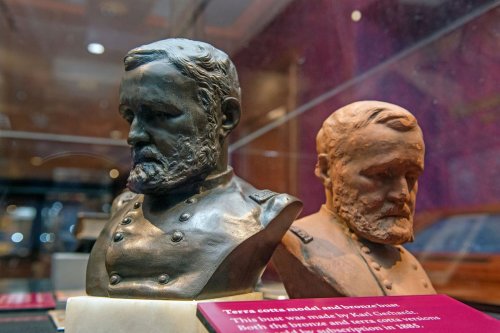 Two busts of a historical figure, one in bronze and one in terracotta, displayed with an informational plaque.