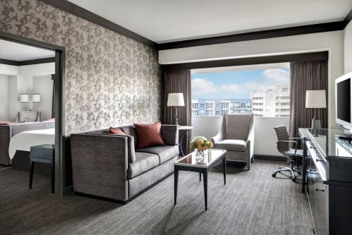 A modern hotel room featuring a seating area, large window, and stylish decor with a view of the city.