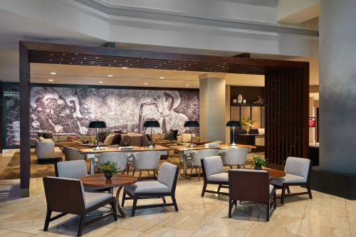 Modern hotel lobby with stylish seating, wooden accents, and a large mural on the wall. Bright and inviting atmosphere.