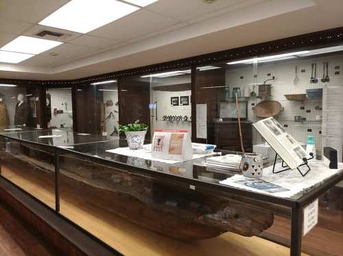 A display case in a museum featuring various artifacts and historical items on a wooden table.