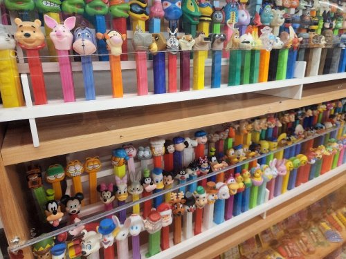 A colorful display of various Pez dispensers featuring cartoon characters on a wooden shelf.