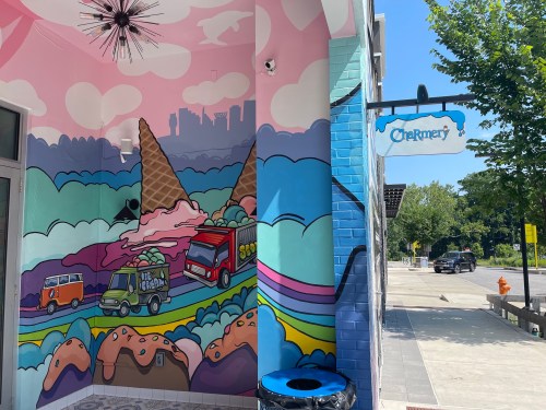 Colorful mural featuring ice cream cones and vehicles, with a sign for "The Creamery" on a sunny day.