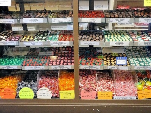 A colorful display of assorted candies and chocolates in a shop window, neatly arranged in boxes.