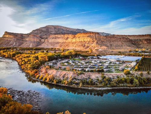 Aerial view of a river winding through a landscape with a campground and rocky cliffs in the background.