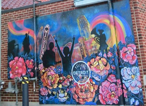 Colorful mural featuring silhouettes, flowers, and "Filling Detroit Street" with a vibrant background.