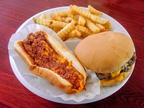 A plate with a chili cheese dog and a cheeseburger, accompanied by a side of crinkle-cut fries.