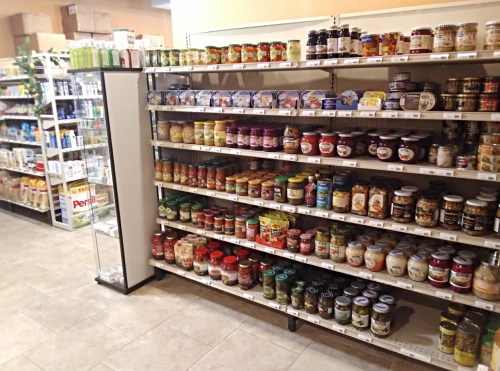 A grocery store aisle with shelves stocked with various jars, sauces, and canned goods.