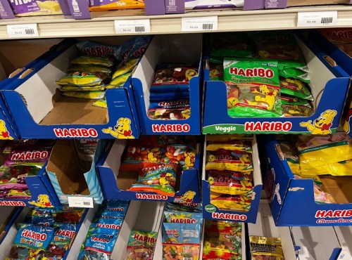 Shelves filled with colorful Haribo candy bags in blue boxes, some boxes partially empty.