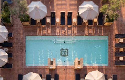 Aerial view of a serene pool surrounded by lounge chairs and umbrellas, set in a stylish outdoor area.