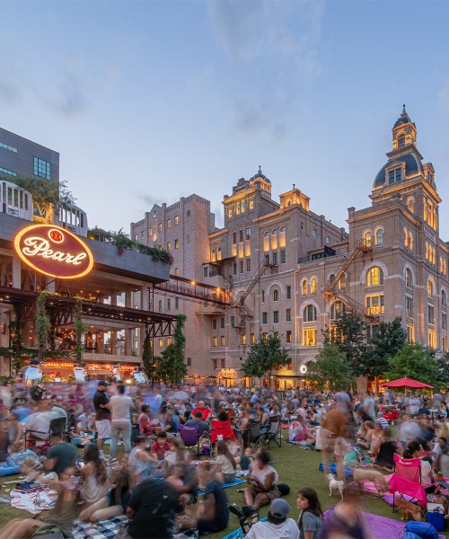A lively outdoor gathering at Pearl, with crowds enjoying the evening near historic buildings and vibrant lights.