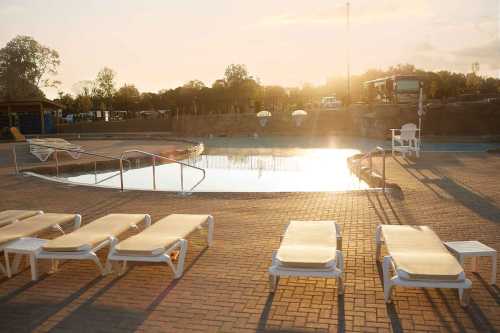 Sunset over a tranquil pool area with lounge chairs and a serene atmosphere.