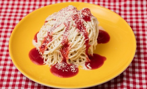 A plate of spaghetti topped with red sauce and grated cheese, served on a yellow plate with a checkered tablecloth.