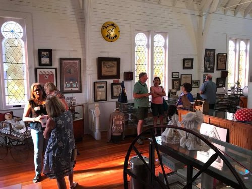 A lively gathering in a museum with people interacting among various exhibits and historical artifacts.