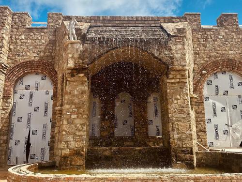 A stone fountain with water cascading down, set against a backdrop of brick walls and construction materials.