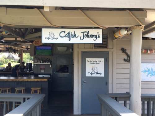 Sign for "Catfish Johnny's" restaurant with a bar area visible in the background.