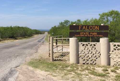 Sign for Falcon State Park at the entrance, with a road leading into the park and greenery on either side.