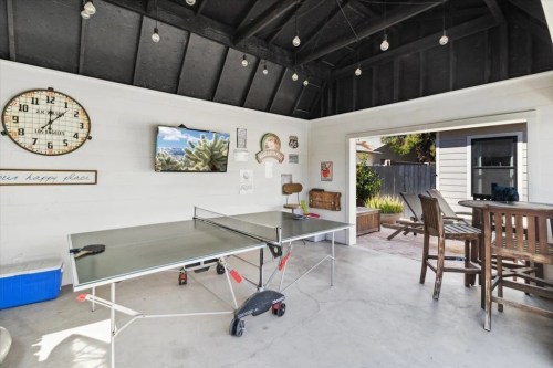 A spacious outdoor game area featuring a ping pong table, seating, and decorative wall art.