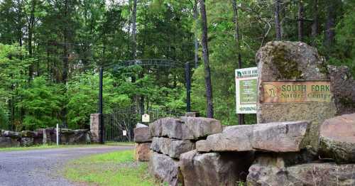 Entrance to South Fork Nature Center, featuring stone signage and a lush green forest backdrop.