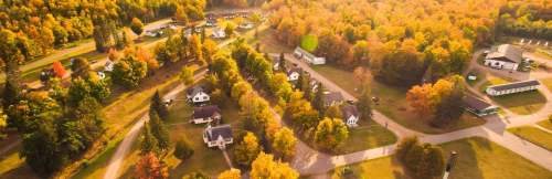 Aerial view of a scenic neighborhood surrounded by vibrant autumn foliage and winding roads.