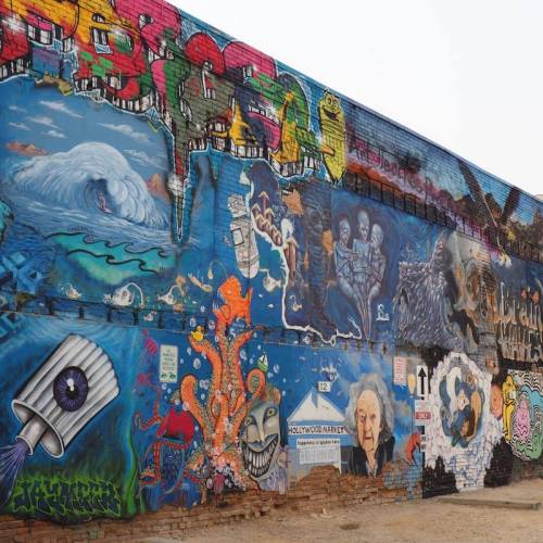 Colorful mural featuring abstract designs, ocean waves, and various characters on a brick wall.