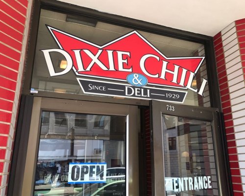 Sign for Dixie Chili & Deli, established in 1929, with an open door and a welcoming entrance.