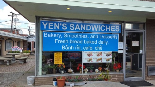 Sign for Yen's Sandwiches featuring bakery, smoothies, and desserts, with fresh bread baked daily. Bánh mì, café, chè.
