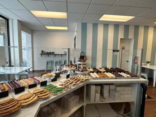 A bakery display featuring a variety of cookies, pastries, and desserts on a counter in a bright, modern space.