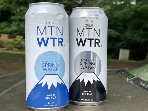 Two cans of Izumi MTN WTR: one still spring water and one sparkling, both featuring a mountain design.