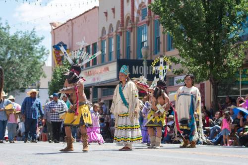 A vibrant parade scene with dancers in traditional attire, showcasing cultural heritage under a sunny sky.