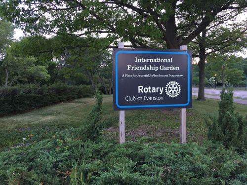 Sign for the International Friendship Garden, featuring the Rotary Club of Evanston, surrounded by greenery.