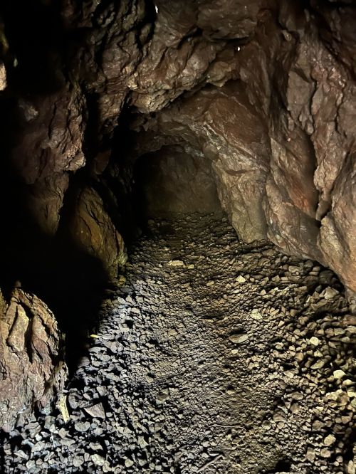 A dark cave interior with rocky walls and a stony path leading deeper into the tunnel.