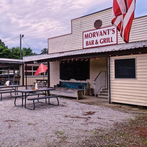 Exterior of Morvant's Bar & Grill featuring outdoor seating, an American flag, and a rustic building design.