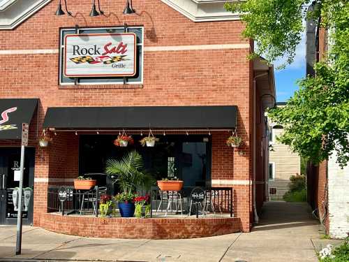 Exterior of Rock Salt Grille, featuring a brick facade, outdoor seating, and hanging flower pots.