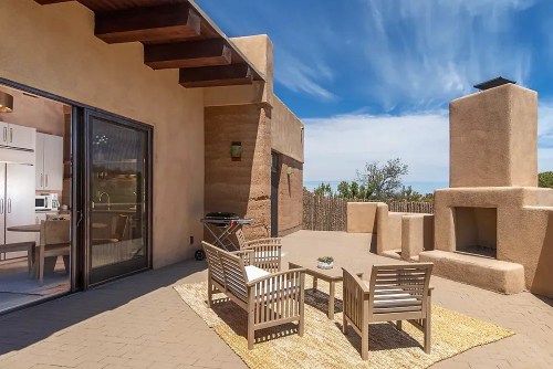 A cozy outdoor patio with wooden furniture, a fireplace, and a view of the sky and surrounding landscape.