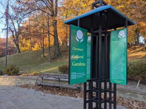 Signpost for Cleveland Cultural Gardens, surrounded by autumn trees and a park bench in a scenic outdoor setting.