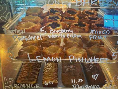 A display case filled with various pastries, including lemon pinwheels, blueberry, and mixed fruit options.