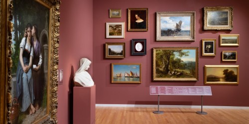 Art gallery interior featuring various framed paintings and a bust sculpture against a maroon wall.