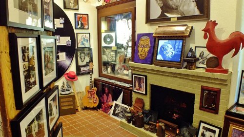 A cozy room filled with framed photos, artwork, and memorabilia, featuring a fireplace and a guitar.